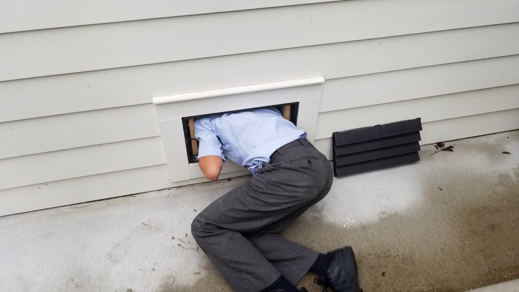 child crawling through a wall opening during a home inspection